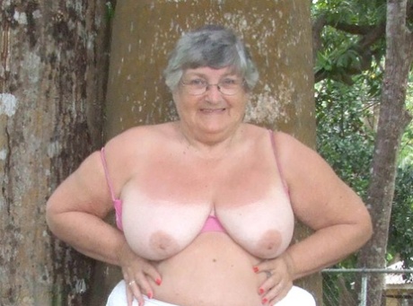 Great Britain's elderly woman, Grandma Libby, exposes her massive breast implants beneath a tree.