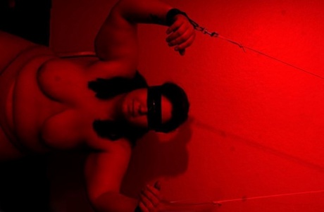 The Inked Oracle, a heavyset member of the group, is tied up after being blindfolded on a bed.