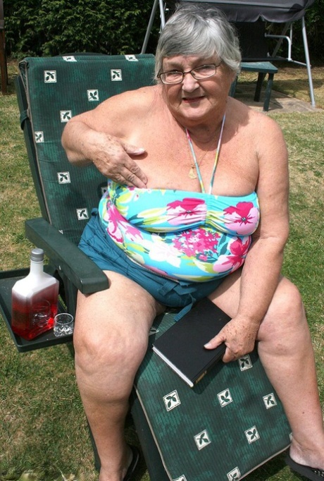 Naughty granny Libby inserting a bottle into her large vagina in the garden.