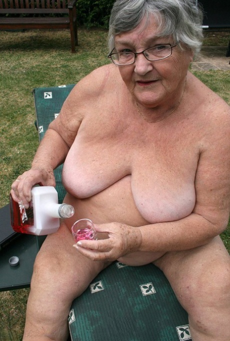 The sly granny in the garden, inserting some liquid into her large vagina.