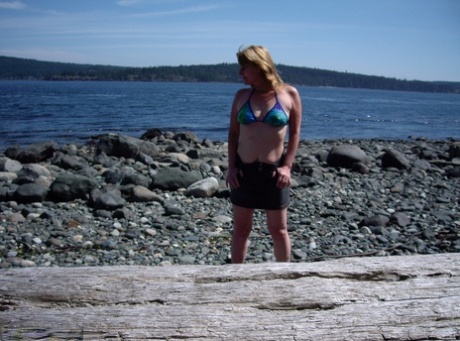 The middle-aged Cougar Babe Loleé removes her swimsuit from a sandy beach on the coast.