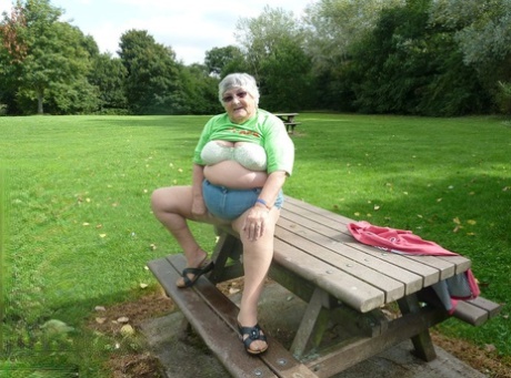 A picnic table is used by obedient Grandma Libby to display her large tits and buttocks.
