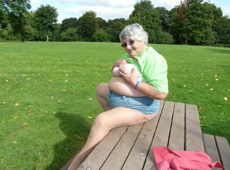 On a picnic table, Obsession Mom named Grandma Libby displays her large breasts and buttocks.