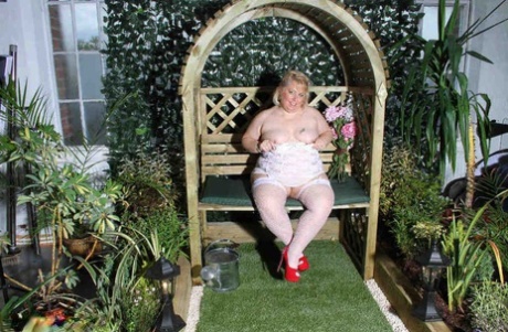 Lexie Cummings, a full-figured blonde, uses a dildo in her garden to stimulate her pussy.
