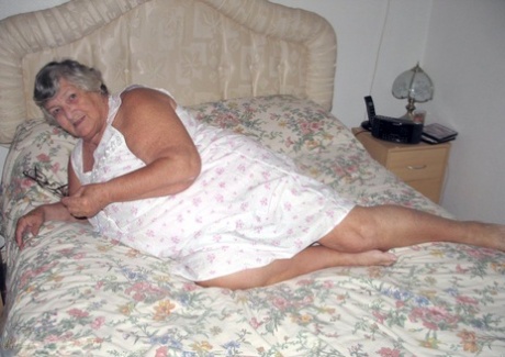 The naked woman, Grandma Libby, grabs her fat roll after getting up on the bed.