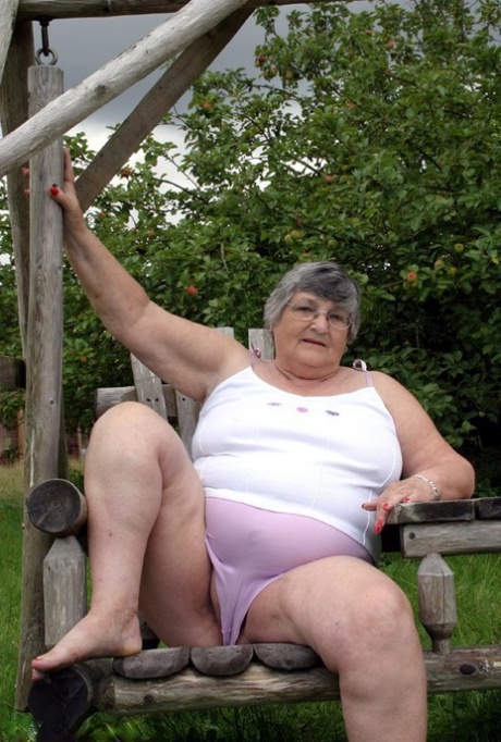 On a bench swing in the backyard, Grandma Libby, an elderly British woman, displays her breasts.