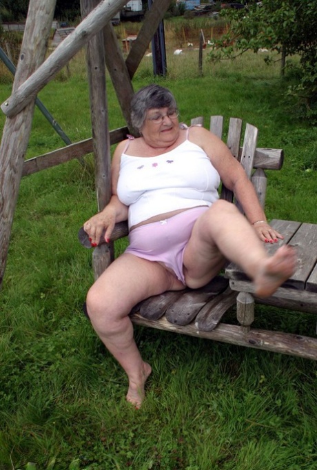 Grandma Libby, an elderly British woman, showcases her breasts on a bench in the backyard.