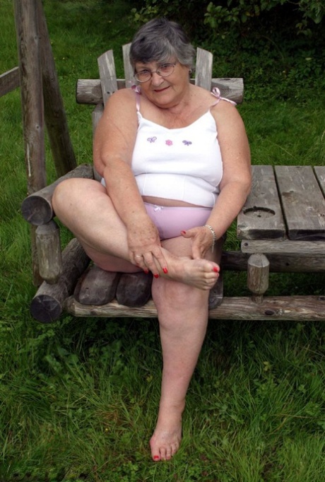 An elderly British woman named Grandma Libby flaunts her breast tissue on a bench in the backyard.