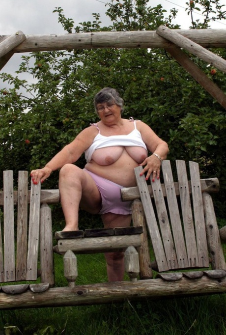 Grandma Libby, an aged British woman who is both elderly and beautiful, flaunts her chest on a bench in the backyard.