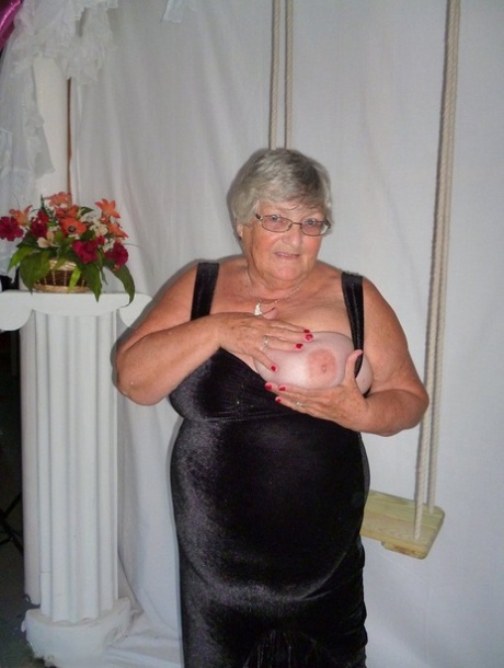 The model, Grandma Libby, removes her clothing from a black dress and models the nude look in stockings.