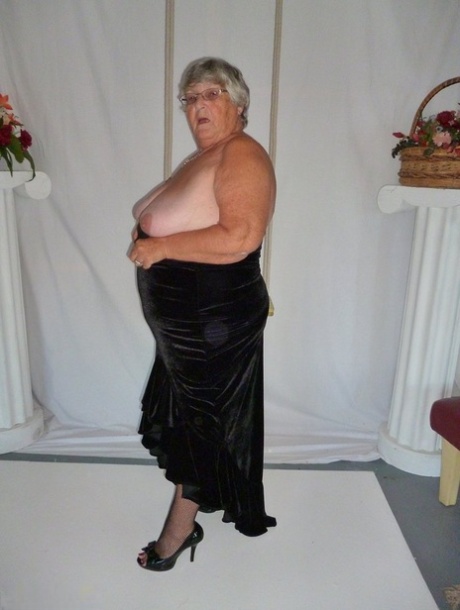 Unadorned in stockings, Grandma Libby takes off her clothes and wears a black dress to pose for a photo.