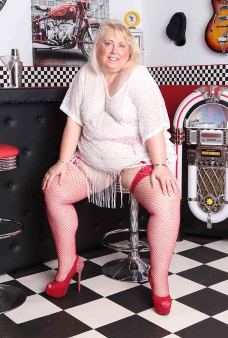 In front of a diner, Lexie Cummings, a blonde who is overweight, exposes herself in red fishnets.