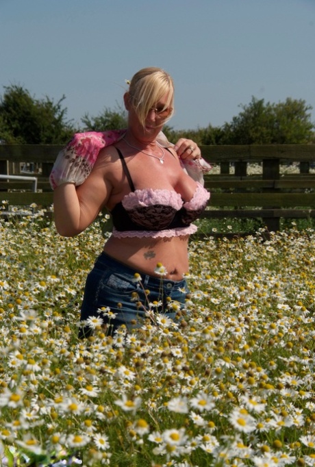 Overweight blonde Melody unclipse her large breasts in a field of wild flowers.