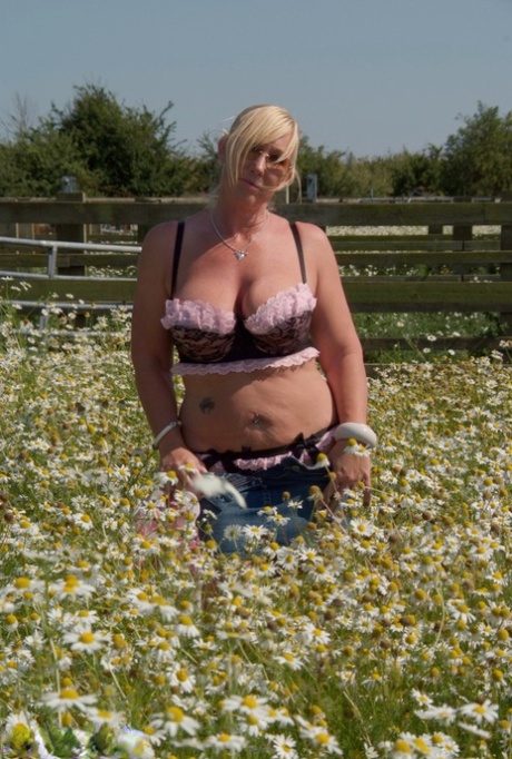 In a field of wild flowers, the overweight blonde Melody unclipse her large breast tissue.