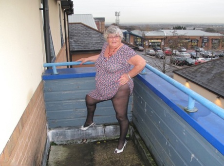 On a balcony, Grandma Libby, a fat UK woman, exposes her breasts before getting naked.
