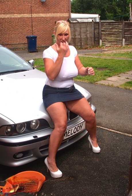 While washing her car, blonde amateur with big tattoos like Melody soaks in a white T-shirt.
