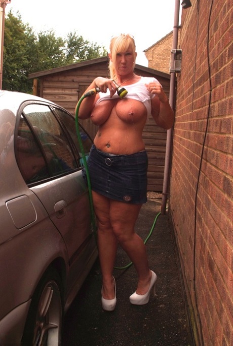 Blonde Melody with a lot of tattoos washing her car while wearing white T-shirts.