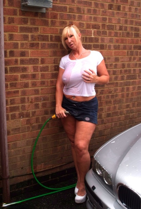 A white T-shirt is soaked in Melody, an amateur hairstyle with big tattoos, while she washes her car.