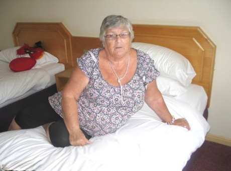 A silver-haired British lady named Grandma Libby exposes her plump figure on a bed.