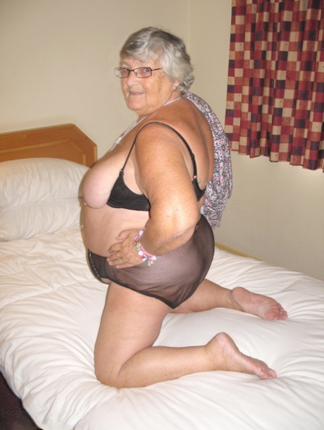 Grandma Libby, an overweight woman from Britain with silver hair, exposes herself on a bed.