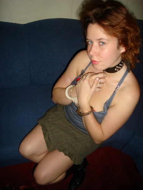 The natural redhead, dressed in boots and handcuffs, wears a ball gag before masturbating.