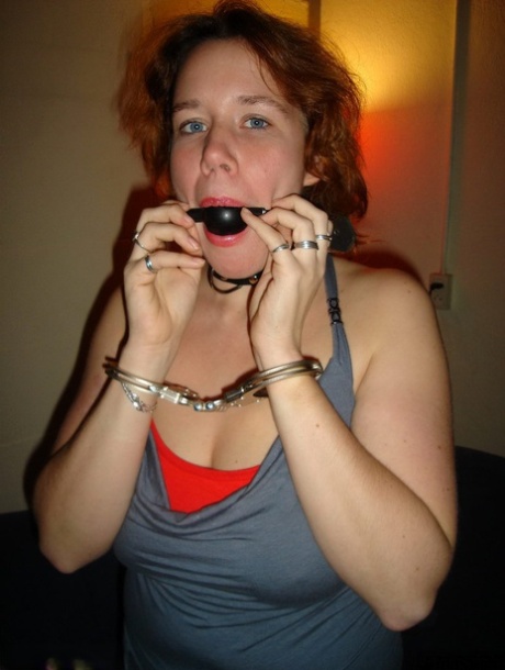 Excessive redhead wears boots and uses a ball gag and handcuffs before masturbating in public.