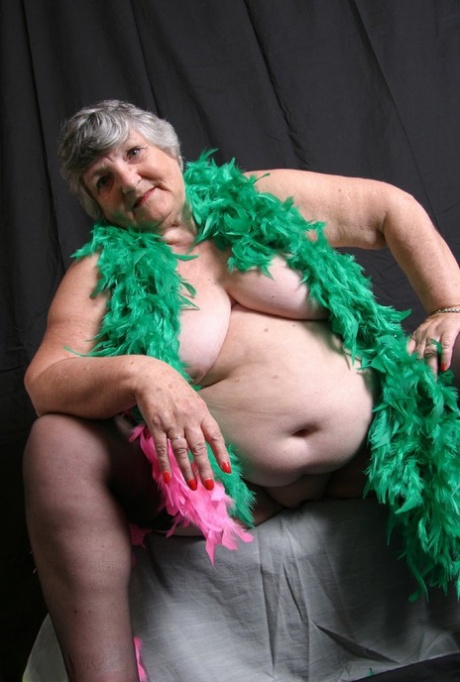 Despite her body being fat and not well-fitted, Grandma Libby from the UK displays her big tits while wearing feather boas.
