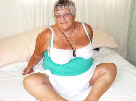 Толстая бабушка с короткими волосами и огромным животом засовывает дилдо в свою киску