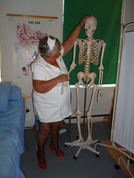 Grandma Libby, a fat and elderly nurse, secures a dildo to a skeleton for sexual stimulation.