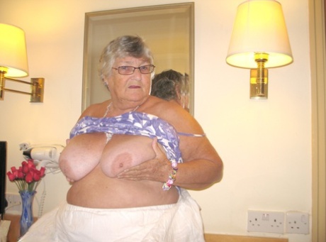In a hotel room, Grandma Libby (a fat British woman) completely removes her clothes.