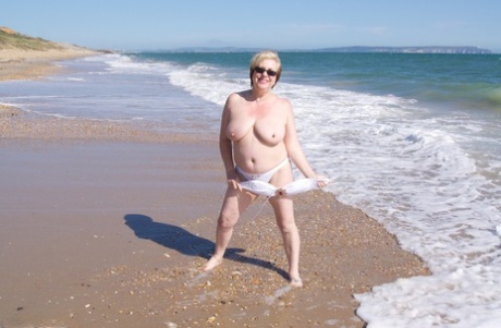 Speedy Bee, an adult of average appearance, exposes herself in shades on a beach in Britain.