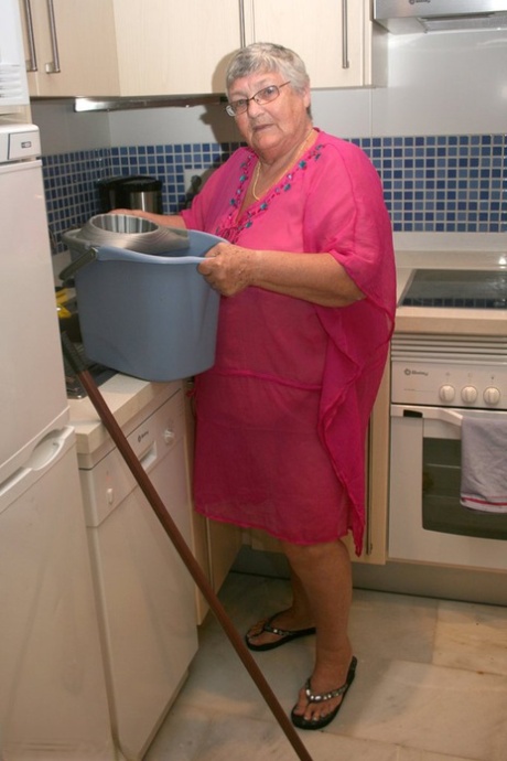 Grandma Libby, who is fat and from the UK, gets naked while cleaning her kitchen.