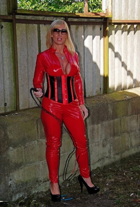 Sexy adult blonde Melody uses a whip as she pulls out the hemlines from some of the red latex clothes.