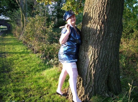 A police uniform is worn by an old redhead named Valgasmic Exposed as she lies exposed by a canal.