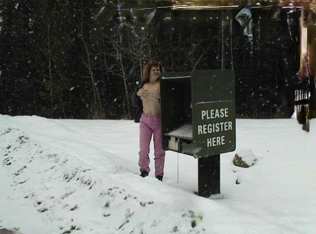 Misha MILF is an adult who stands naked on snowy terrain.