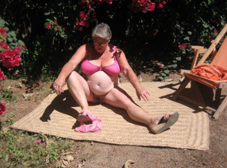 The elderly lady, the Grim Grime Goddess, bares herself on the garden patio while wearing her sandals.