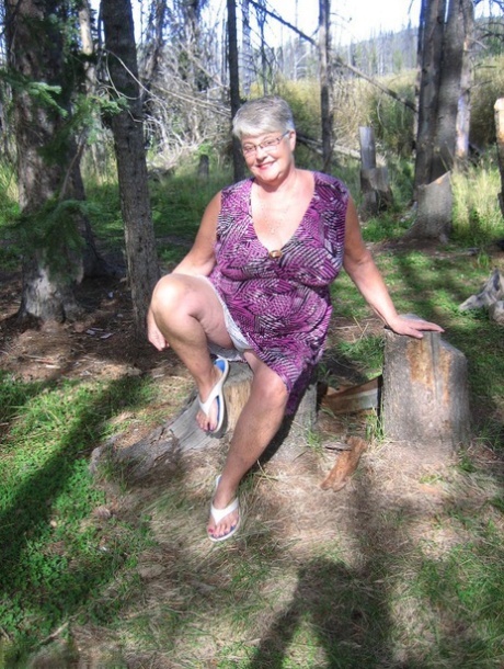 Fat granny Girdle Goddess bares her purple attire in the wooded area and poses without clothes.