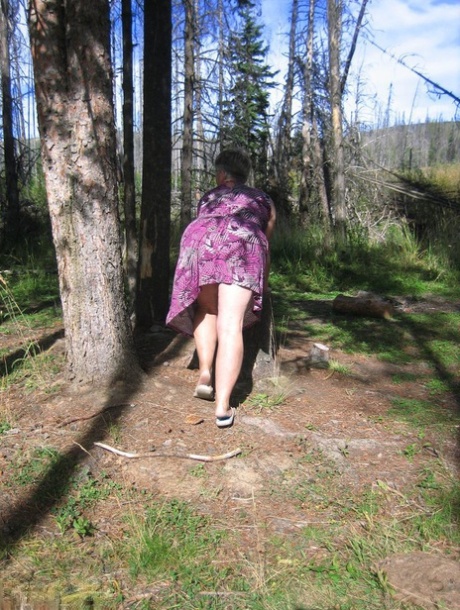 In the woods, the Fat Girdle Goddess goes from wearing her purple outfit to posing in the nude.