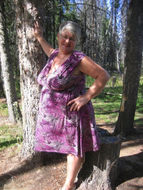 Fat grandmother Girdle Goddess takes off her purple attire in the woods and poses without clothes.
