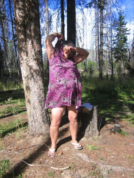 After shedding her purple attire, the Fat Girdle Goddess takes to the woods and poses without clothes.