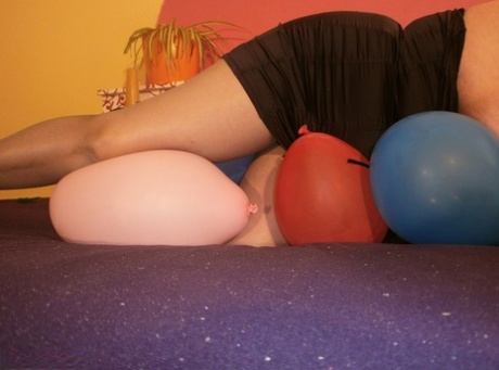 The older blonde, overweight woman named Caro is attempting to crush balloons on top of her bed.