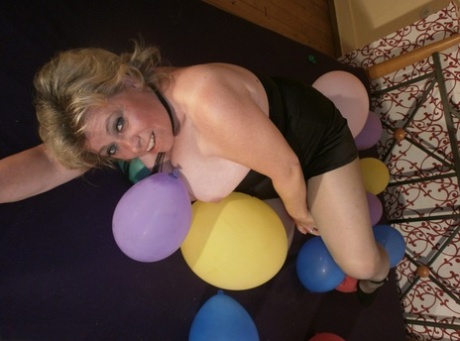 With a busy build, the older blonde Caro tries to crush balloons on top of her bed with her arms.