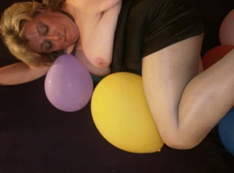 Caro, an older blonde and overweight woman, endeavors to crush balloons on her bed.