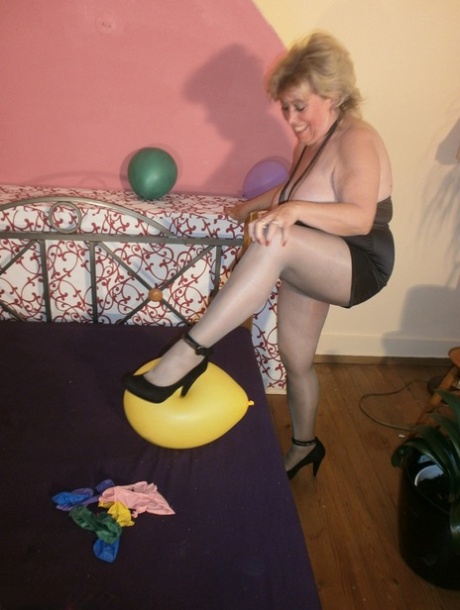 Caro, a young lady, exposes her stomach area in pantyhose while hanging out with balloons on her bed.
