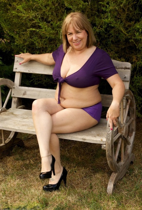 A garden bench is used by Speedy Bee, an older British amateur who is naked in heels.