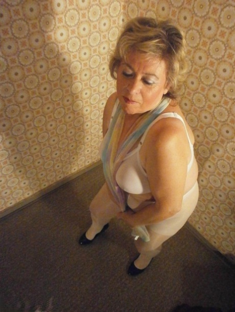 A large and mature woman named Caro, who is dressed in white pantyhose and black high heels,