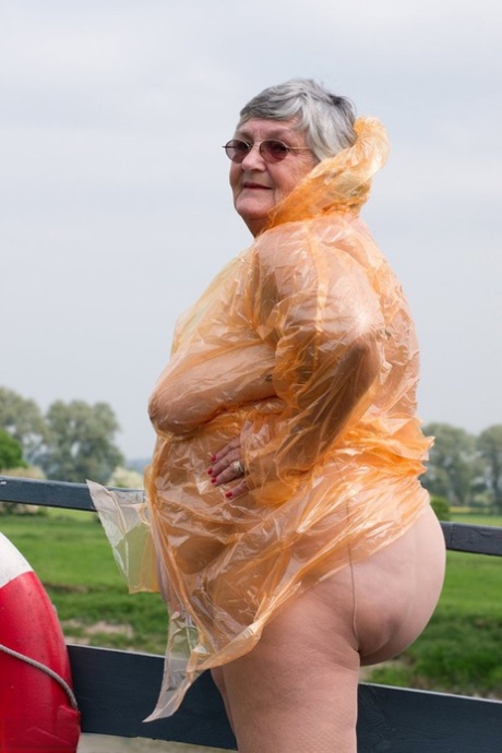 Grandma Libby, an obese British amateur, removes her raincoat that is transparent.