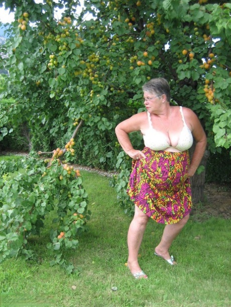 The fat granny girdle Goddess displays her large tits beneath a fruit tree.