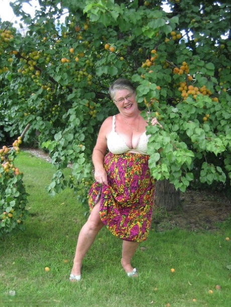 Fat granny girdle Goddess displays her large tits beneath a fruit tree.