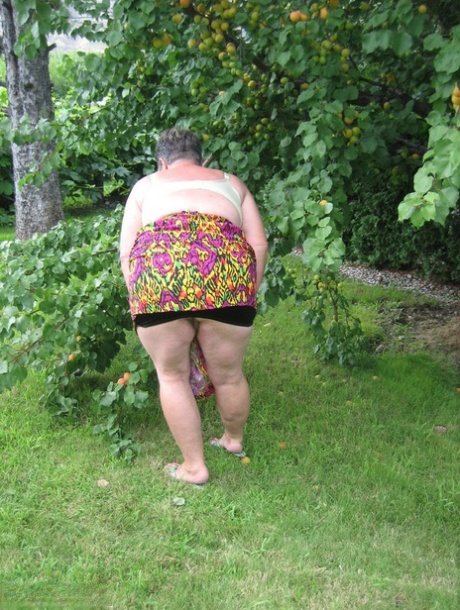 Fat Granny Girdle Goddess displays her enormous tits beneath an apple tree.